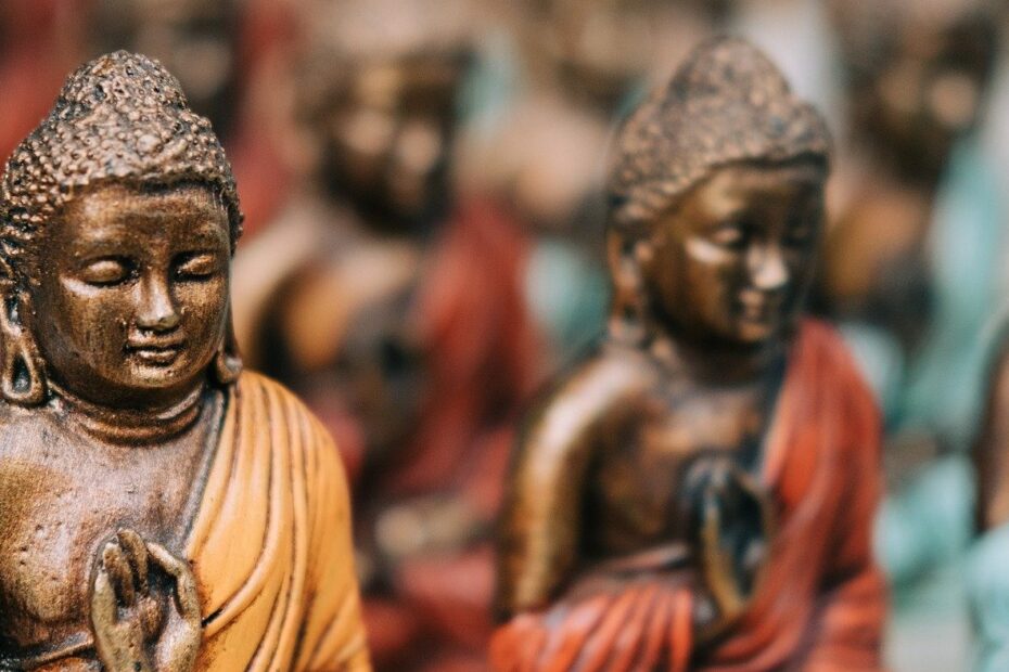Immagine con tante statuette di Buddha con drappi colorati.